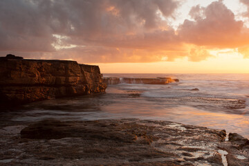 Golden orange light of sunrise across the beach seascape