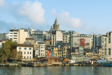 Fototapeta na wymiar Galata Tower with old houses, Karaköy pier and sea view. Cloudy sky.