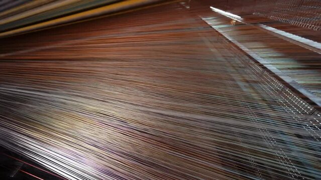 Yarn thread lines on the weaving loom machine in textile factory. Textile machine with red and yellow threads. Carpet factory, carpet production. Close up, 4K