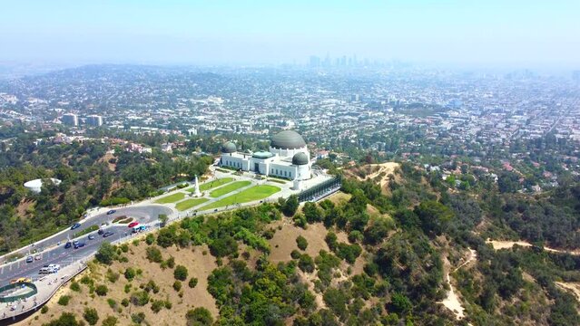 Hazy outline of Los Angeles city and skyline. Griffith Observatory in foreground. Drone ascending. 