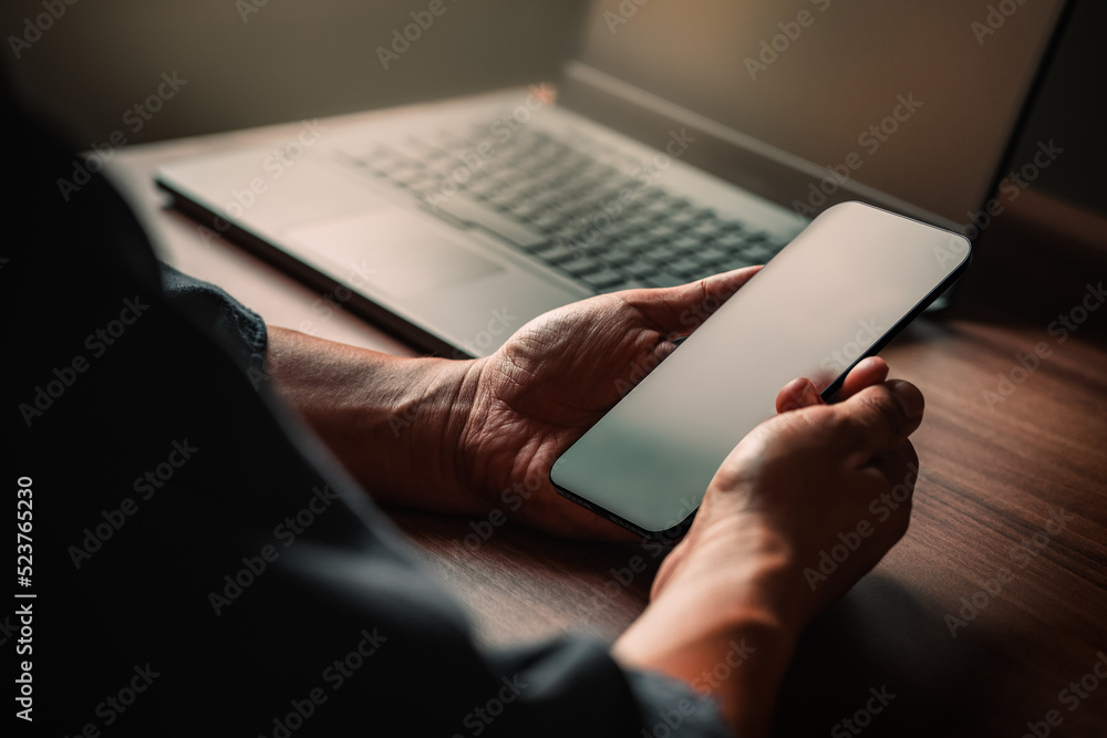 Poster Mockup image of a man holding and using smartphone with blank desktop screen while working and drinking coffee in cafe.