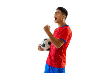 Portrait of young emotive man, motivated football player in uniform with ball posing isolated over...