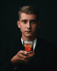 Tasting, tasting. A man in a suit holds a glass of brandy. Tasting and wine tasting concept. Young businessman in an elegant suit with a glass of whiskey. Sommelier tastes an expensive drink.