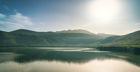 Fototapeta premium Sunrise landscape over lake and mountains with cloudy sky.