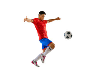 Portrait of young man, football player training, playing, kicking ball isolated over white studio...