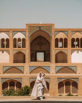 Woman in traditional wear standing near mosque