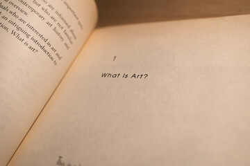 'What is Art?' quote on old book paper, art themed text.