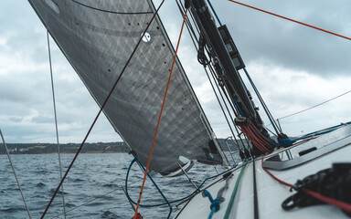 Yacht sailing in the sea. Close-up view of the deck, mast and sails with cloudy sky.
