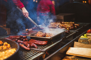 Outdoor street food festival. Chief cooking sausages, meat and potatoes cooking on an outdoor...
