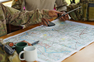 Army ranger military special force hold a cup drink coffee discussion looking pointing at the war map on table and GPS to mark up location plan before attact enemy
