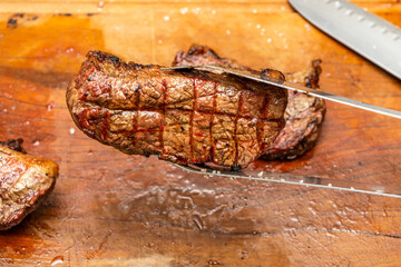 a barbecue tong holding grilled tri-tip steak