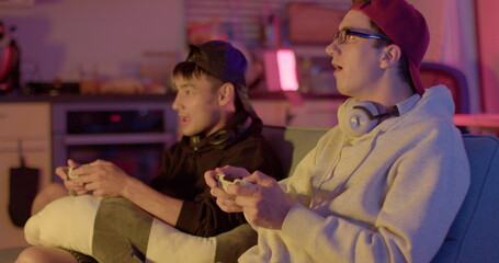 Spending time with a friend. They are playing a video game, ending the game. They make a friendship gesture ritual. Living emotions. Emotional ending of the game in the evening in the room.