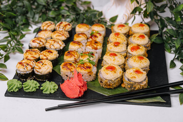 Served warm sushi with ginger and wasabi on a black stone plate