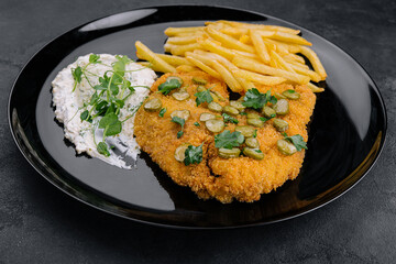Delicious wiener hunter schnitzel with sauce and french fries close-up on a plate
