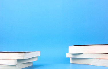 Books place on two side of blue background. Composition with different school stationery light blue background. Back to school concept design and space for text