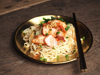 Chinese BBQ pork noodles in golden dish on wooden background