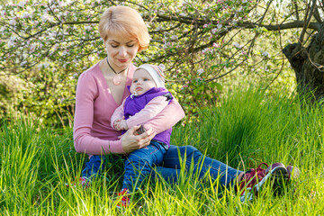 Fototapeta premium Beautiful girl in the arms of a child girl in a blooming park