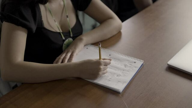 Details of a Native American female student's hand and notebook doodling in design class. 