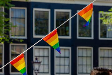 Celebration of pride month in Amsterdam, Rainbow flags hanging outside building along street,...