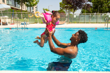 Mixed race father and daughter having fun in pool