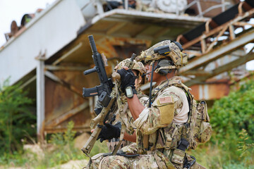 2 Army military soldier in the battle field sitting knee down on the ground hold the gun alert look...