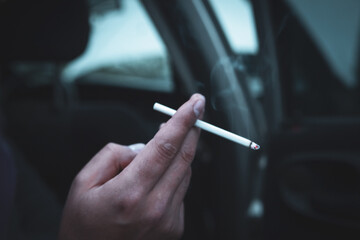 a man sits in a car and smokes