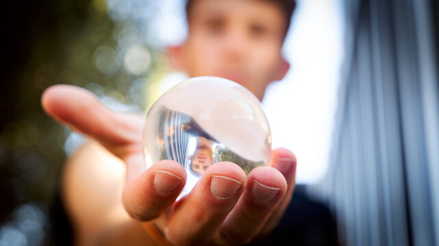 hand holding a crystal ball with the reflection of a guy