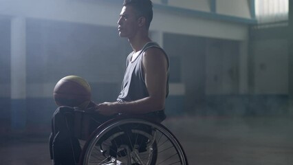 Disabled athlete in a wheelchair with dramatic lighting holding ball