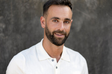 Portrait of smiling handsome latin man with beard and stylish hair looking at camera isolated on grey background. Barbershop service concept
