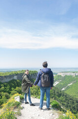 Fototapeta na wymiar Couple of male and female tourists hold each other's hands as they reached the top and enjoy the view. Adventure hiking hiking hiking. Top. Man with a backpack