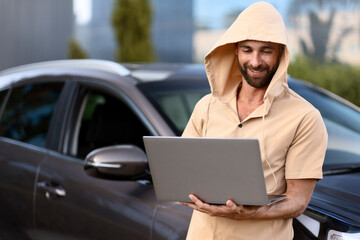Cunning bearded latin man trying to steal car using laptop and hacker software. Сarjacking concept 