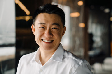 Portrait of midaged smiling asian businessperson in shirt looking straight