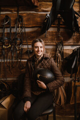 Fototapeta na wymiar Young jockey woman using mobile phone while sitting in stable