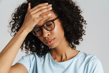 Black curly woman in eyeglasses with headache holding her forehead