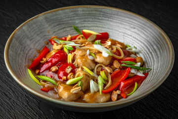 Thai chicken pasta in a ceramic plate on a dark textured background. Restaurant menu Isolated on black