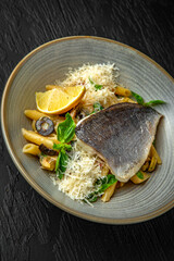 Penne pasta with dorado and parmesan in a ceramic plate on a dark textured background. Restaurant menu Isolated on black