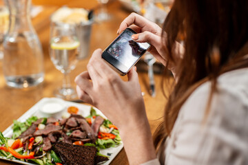 technology and people concept - close up of woman with smartphone photographing food at restaurant