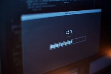 cybercrime, hacking and technology concept - close up of computer monitor with progress loading bar on screen in dark room