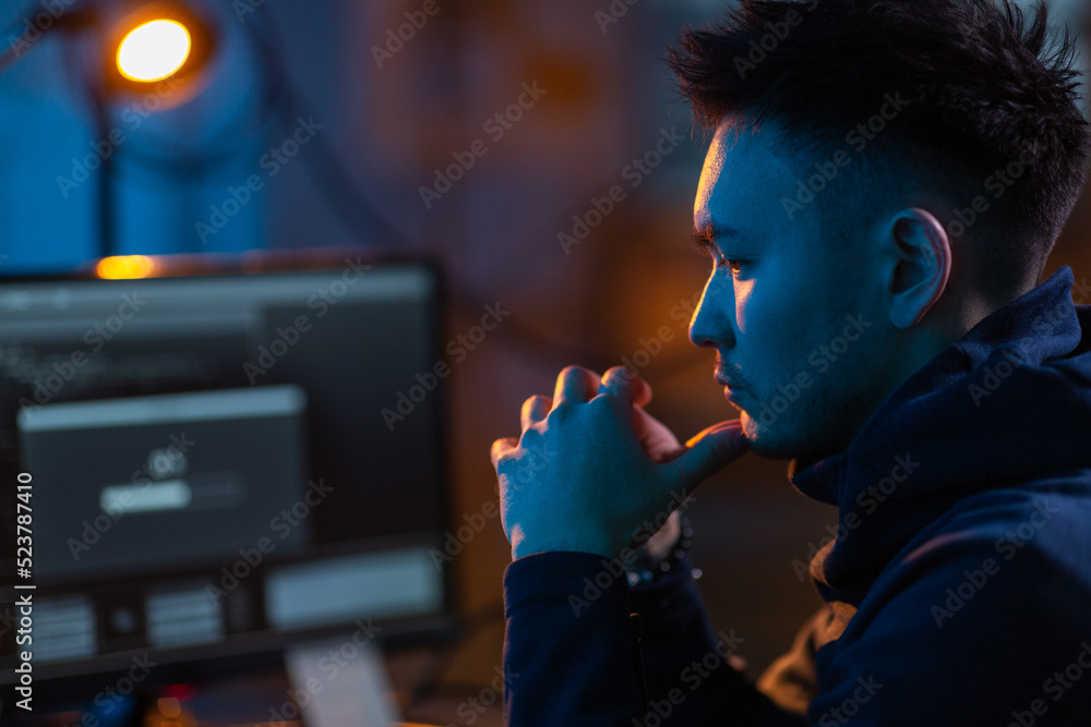 Poster cybercrime, hacking and technology concept - close up of male hacker in dark room using computer vir