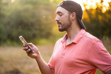 A man is talking on the phone. Distance Learning. Online communication. A guy holds a smartphone in his hands at sunset.