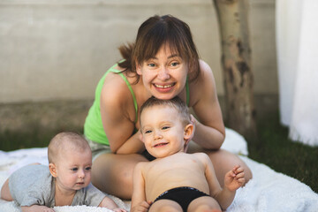 Obraz premium The mother of two children plays with them and enjoys life. A mother and her two children. Mother of two. Happy motherhood.