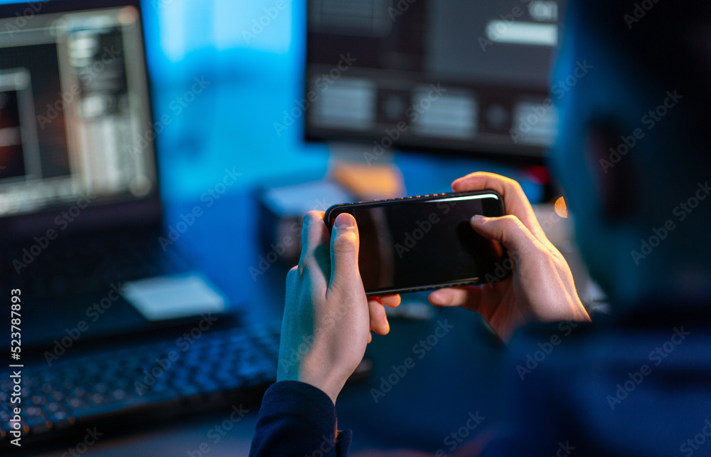 Poster cybercrime, hacking and technology concept - close up of male hacker with smartphone using computer 