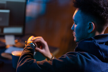 cybercrime, hacking and technology concept - close up of male hacker in dark room with smart watch...