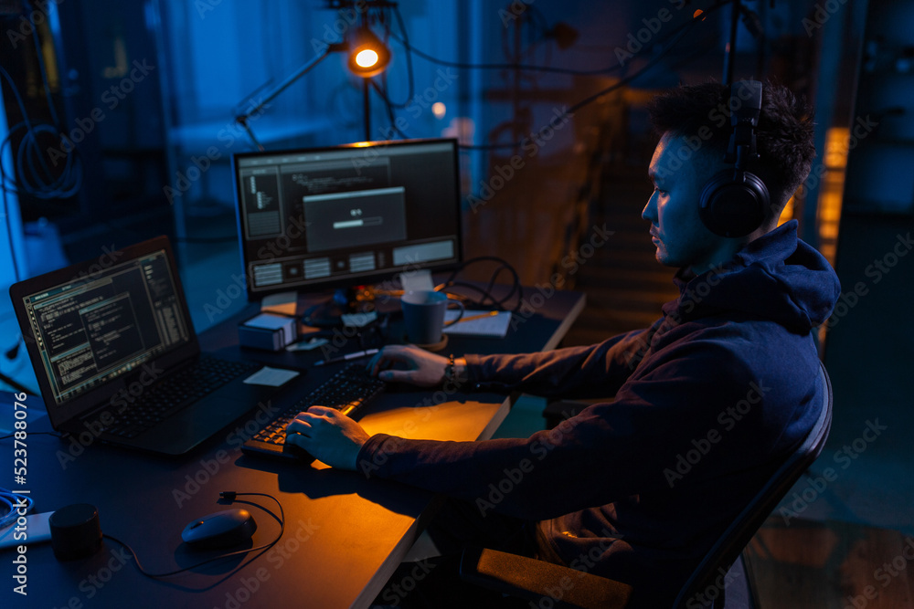 Poster cybercrime, hacking and technology concept - male hacker in dark room writing code or using computer