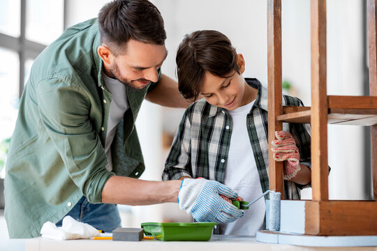 Renovation, Diy And Home Improvement Concept - Father And Son In Gloves With Paint Roller Painting Old Wooden Table In Grey Color