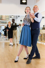 Man and woman dancing waltz in studio