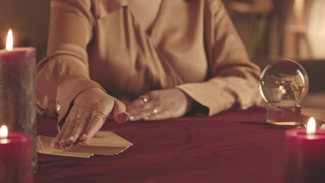 Cropped slowmo of unrecognizable fortune teller using tarot cards while predicting future to client at seance