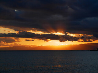 Obraz premium 日本、神奈川県、鎌倉市、雲の隙間から見える七里ガ浜の夕陽