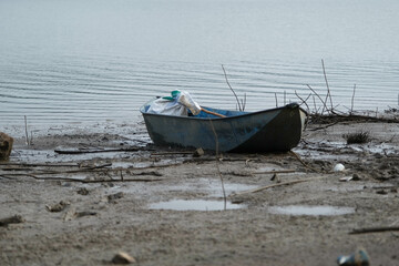 Obraz premium Old boat on the bank of the river among the twigs waste.