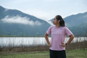 Obraz premium Asian women run in the countryside by the river in the morning and rest after training. Sports and recreation healthy lifestyle concept.